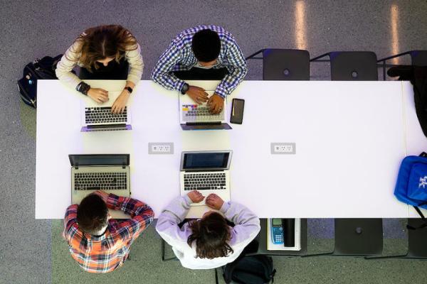 Overhead photo of four people working on computers.