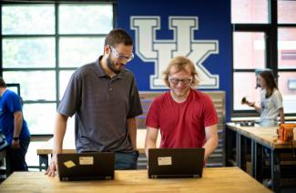Two people working on computers with goggles. 