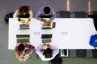 Overhead photo of four people working on computers.