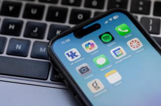 Photo of a phone laying on a computer keyboard, with apps showing. 